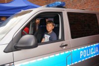 Dzieci w policyjnym radiowozie oraz robiące sobie na pamiątkę odciski swoich dłoni