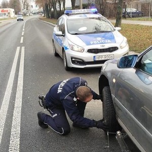 policjant dokręca koło w samochodzie