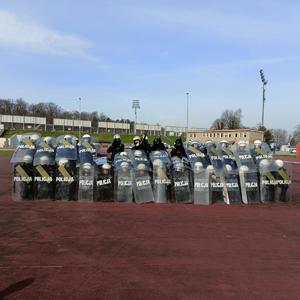 na zdjęciu policjanci z tarczami w szyku zwartym na stadionie
