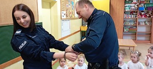 na zdjęciu policjant pokazuje jak zapina się kajdanki